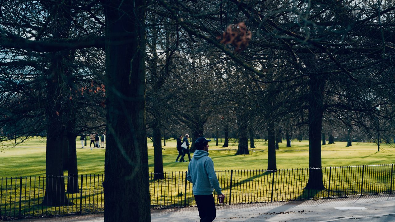 An older adult on a long, unbroken morning walk through a quiet park.