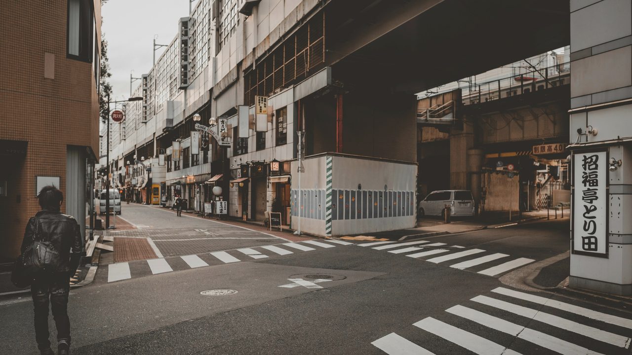 An adult walking briskly along a city street in morning light.